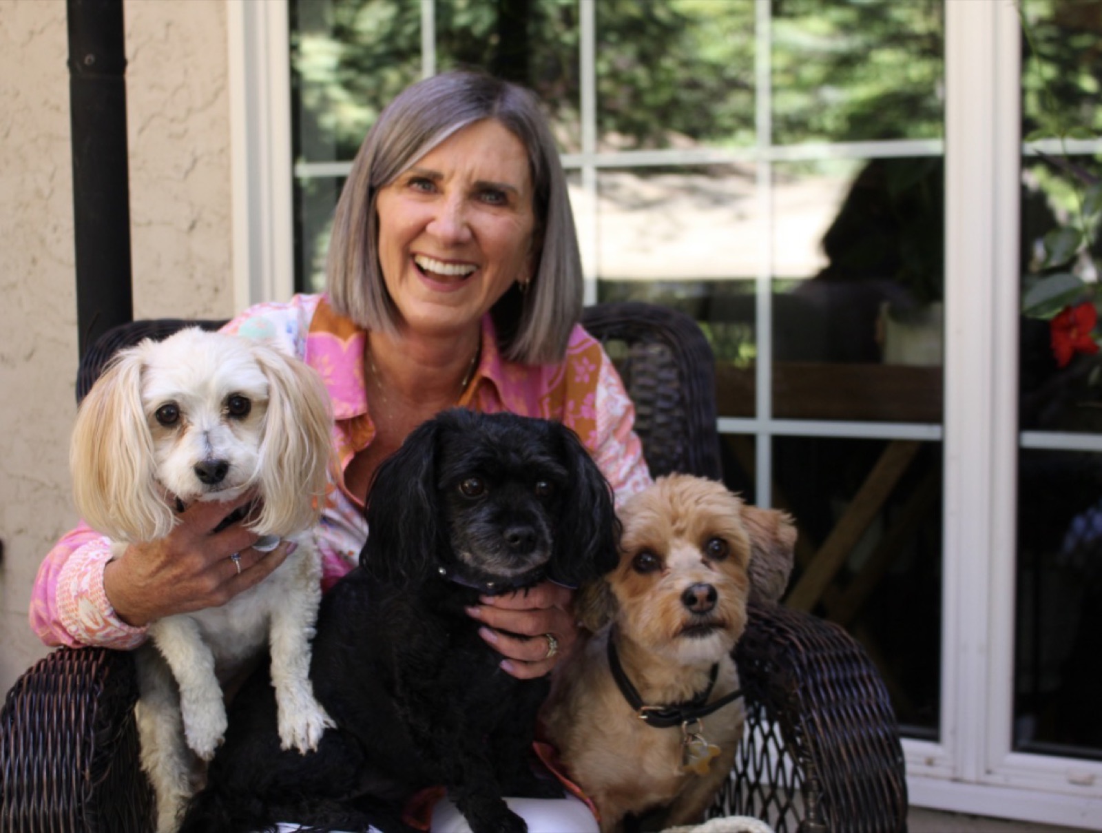 Karen Peters smiling on her porch with her three dogs